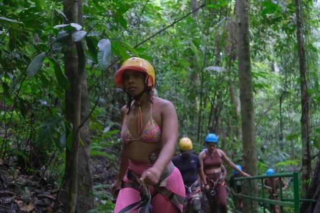 People hiking on a forest path wearing helmets and safety gear.