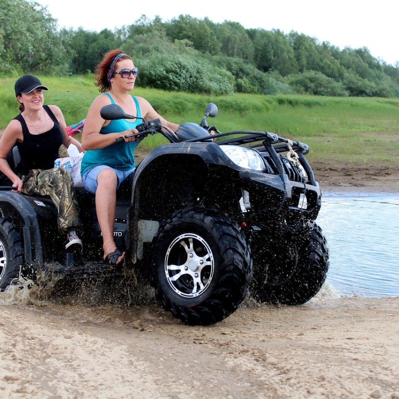 a man and a woman riding a bike down a dirt road